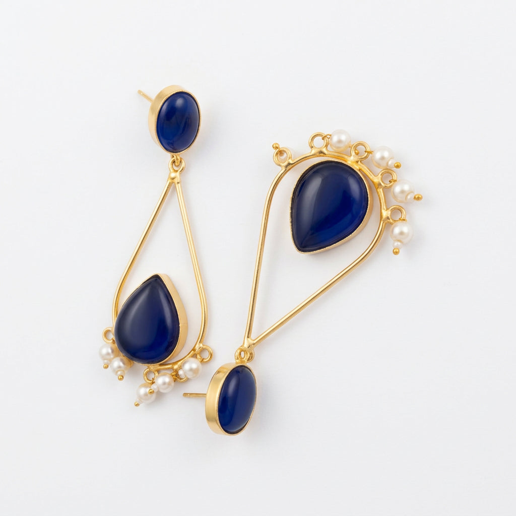 A pair of gold long dangle earrings with deep blue teardrop-shaped stones and small pearl accents,