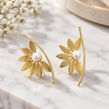 A pair of gold flower-shaped earrings with white pearl centers.