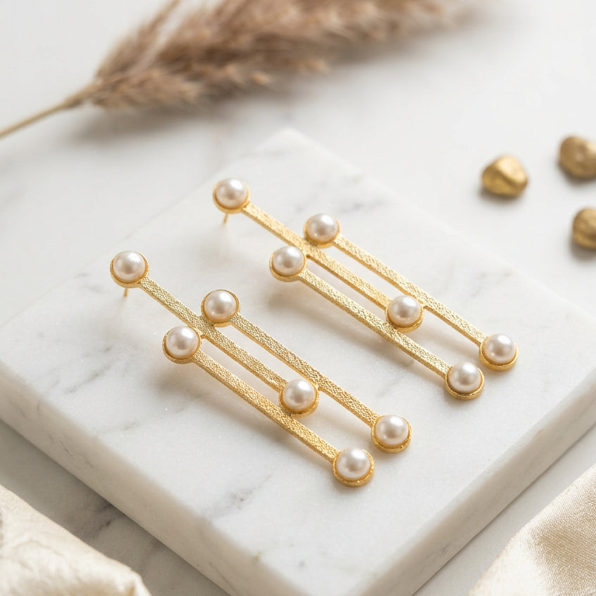 A pair of gold-toned drop earrings with five white faux pearls.