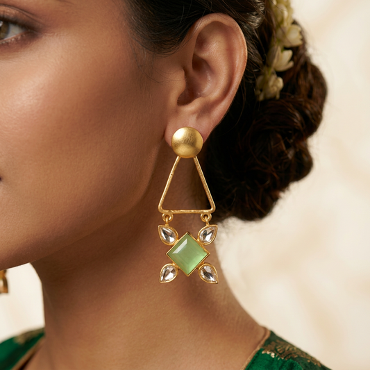 A pair of gold-toned dangle earrings with green square stones and silver teardrop accents, made in pure brass.