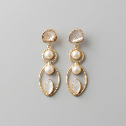 A pair of gold drop earrings with white faux pearls and iridescent shell-like beads, made in brass