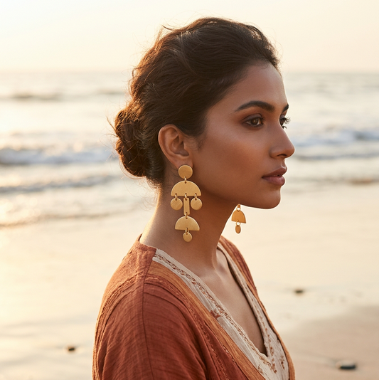 A pair of textured gold geometric dangle earrings displayed on a white foam stand, 